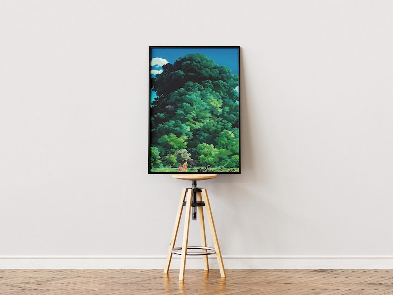 May include: A framed art print depicting a dense green forest under a blue sky. The artwork is presented on a wooden and metal adjustable stool. The print's colours include shades of green, blue, and brown.