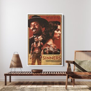 May include: A framed movie poster with a white border. The poster features actors and the title "Sinners" in a vintage style. The color palette is dominated by shades of red, brown, and black. The poster is displayed on a wooden bench.