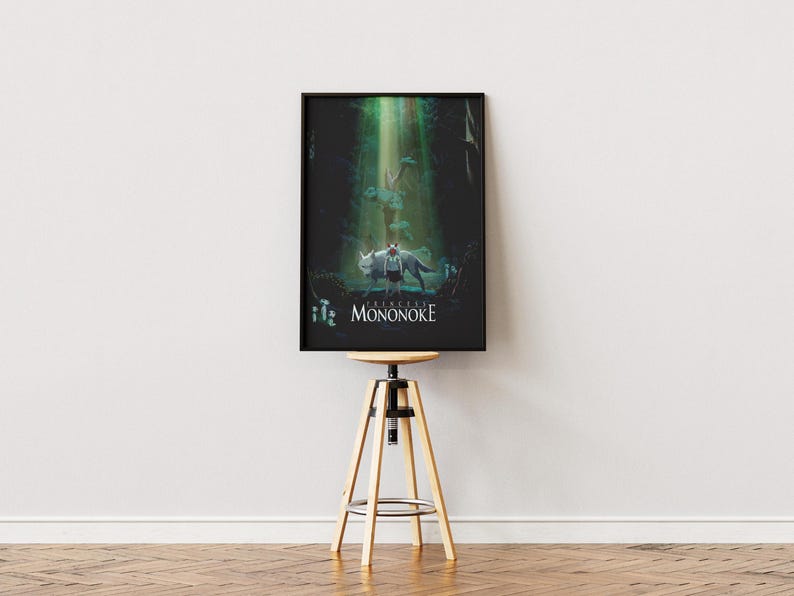 May include: Framed poster featuring a scene from Princess Mononoke. The artwork depicts a figure with a wolf-like creature in a forest setting, with the title text at the bottom. The poster is displayed on a wooden stool.