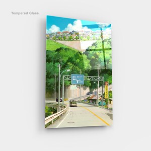 May include: Tempered glass art print featuring a scenic road winding through a lush green landscape under a bright blue sky. The artwork depicts a Japanese town with houses and road signs. A van is driving on the road.