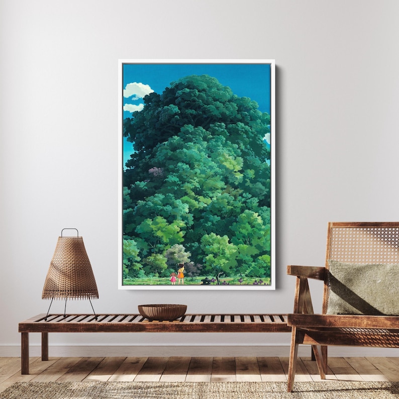 May include: A framed art print shows a vibrant green forest beneath a blue sky with white clouds. Two small figures are in a clearing, giving scale to the tall trees. The artwork is displayed on a white wall, creating a striking contrast.