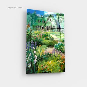 May include: Tempered glass art print featuring a vibrant garden scene with a cottage. The artwork showcases a lush garden filled with colorful flowers, a winding path, and a house with a green roof. The words "Tempered Glass" are printed in the upper left corner.