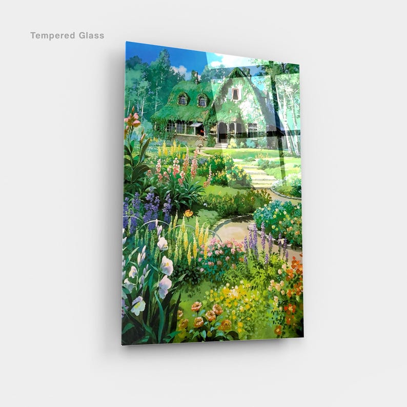 May include: Tempered glass art print featuring a vibrant garden scene with a cottage. The artwork showcases a lush garden filled with colorful flowers, a winding path, and a house with a green roof. The words "Tempered Glass" are printed in the upper left corner.
