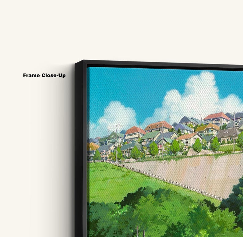 May include: Close-up of a framed canvas print featuring a vibrant illustration of a hillside town under a bright blue sky with fluffy white clouds. The artwork showcases houses with various colored roofs and lush green foliage.