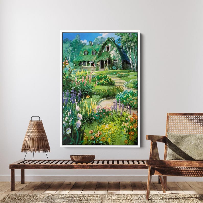 May include: A framed print of a cottage with a green roof, surrounded by a vibrant garden. The artwork features a winding stone path leading to the house, with colorful flowers and lush greenery. The sky is blue with some clouds.