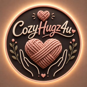 Pu&ograve; includere: Un'insegna da parete circolare con il testo CozyHugz4u in un carattere corsivo rosa chiaro. Il design include un cuore centrale fatto di filato rosa, due mani stilizzate che cullano il cuore, un piccolo cuore di filato sopra e rametti floreali.