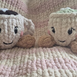 Pu&ograve; includere: Due peluche realizzati all'uncinetto a forma di tazza con volti ricamati, guance rosa e braccia color cuoio. La tazza a sinistra &egrave; color crema con la parte superiore marrone scuro, quella a destra &egrave; color crema con la parte superiore verde chiaro.