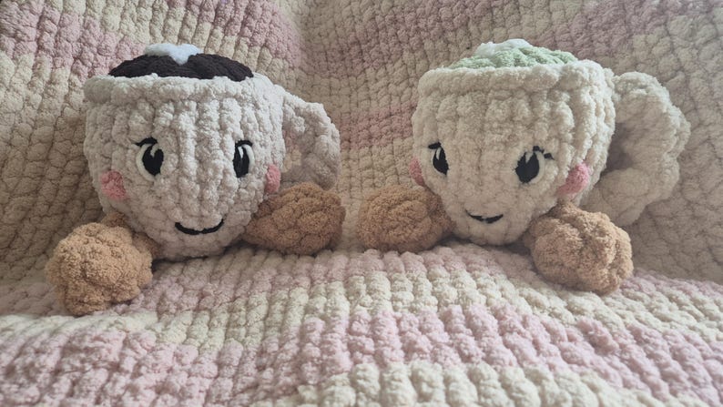 Pu&ograve; includere: Due peluche realizzati all'uncinetto a forma di tazza con volti ricamati, guance rosa e braccia color cuoio. La tazza a sinistra &egrave; color crema con la parte superiore marrone scuro, quella a destra &egrave; color crema con la parte superiore verde chiaro.