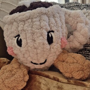 Pu&ograve; includere: Una tazza all'uncinetto in peluche color crema con una parte superiore marrone scuro, un accento a stella bianca e un manico. La tazza presenta occhi neri ricamati, un sorriso nero e piccole guance circolari rosa. Due appendici rotonde e testurizzate.