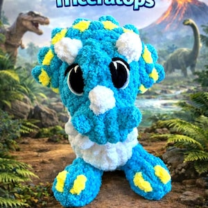 May include: A handmade, plush triceratops dinosaur toy in shades of blue, white, and yellow. The toy has large black eyes and is set against a prehistoric landscape with the text "Snuggle Hatch Triceratops".