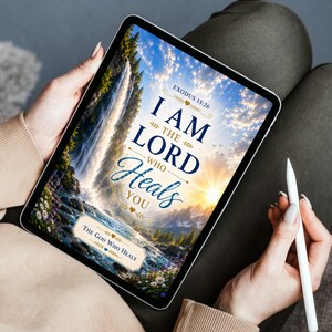 May include: A digital tablet displaying a graphic with a waterfall, a sunrise, and the text Exodus 15:26, I AM THE LORD WHO HEALS YOU, and THE GOD WHO HEALS. The screen features a vibrant landscape with blue, gold, and green tones, held with a white stylus.