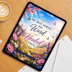 May include: A digital tablet displaying a vibrant landscape with colorful wildflowers, butterflies, and a bright sun. The text reads: PSALM 107:20 HE SENT FORTH HIS Word and Healed THEM. GOD'S WORD BRINGS HEALING AND HOPE. The screen is set on a wooden surface.