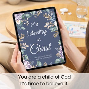 May include: A digital tablet displaying a dark blue background with a floral border and white text that reads My Identity in Christ, Discover who you are through God's word. The screen also features the text, You are a child of God, It's time to believe it.