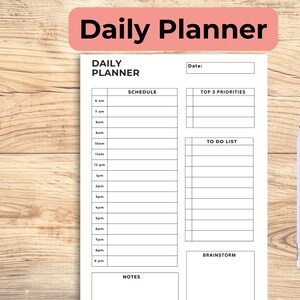 May include: A white daily planner with sections for scheduling, to-do lists, and notes. The planner is labelled "Daily Planner" and includes a light blue pencil. The background is a light brown wood grain.