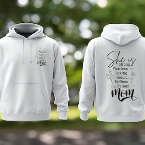 May include: White hoodie with a front pocket and drawstring. The front and back of the hoodie feature the text "She is" followed by a list of positive attributes and the word "Mom".
