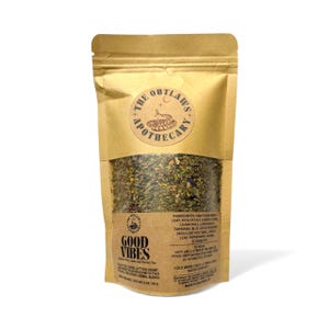 May include: A brown paper bag of "Good Vibes" herbal tea blend. The bag features a circular logo with text and a snake illustration. The tea blend is visible through the clear window, showing a mix of green and purple herbs. The bag also lists ingredients and brewing instructions.