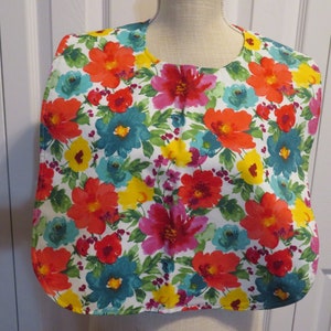 May include: A white bib with a colorful floral pattern. The bib features red, orange, yellow, green, blue, and pink flowers on a white background.