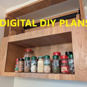 Könnte beinhalten: Gewürzschrank aus Holz mit verschiedenen Gewürzgläsern. Der Schrank ist an einer Wand befestigt und trägt den gelben Text "DIGITAL DIY PLANS". Der Schrank ist aus hellbraunem Holz gefertigt und hat ein Regal mit Gewürzgläsern.