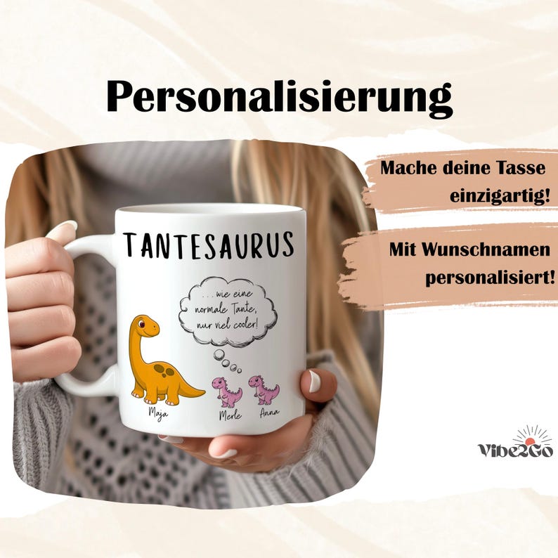 May include: White ceramic mug with the word "TANTESAURUS" in black. The mug features a cartoon dinosaur and the text "...wie eine normale Tante, nur viel cooler!" in a thought bubble. Additional text includes names and the word "Personalisierung".