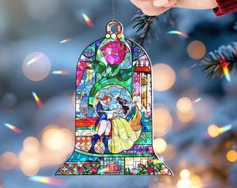 May include: A stained glass ornament featuring a romantic scene with a rose and two figures dancing. The ornament has a bell shape with a gold-colored top and a chain for hanging. The colors include red, yellow, blue, and green.