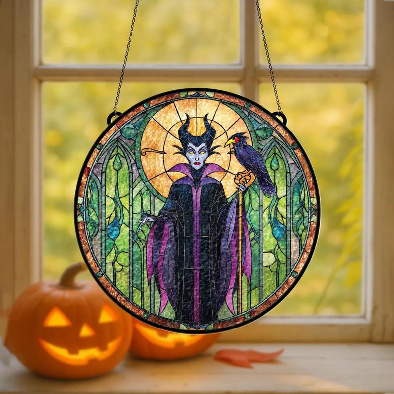 Puede incluir: Ventana redonda de vidrieras con una imagen estilizada de un personaje con cuernos, un cuervo y un bast&oacute;n. La ventana tiene un marco negro y est&aacute; suspendida por una cadena. El fondo es una mezcla de verde, amarillo y naranja, con un tema de Halloween.