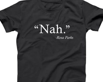 May include: Black t-shirt with the quote "Nah." in white, attributed to Rosa Parks. The text is centered on the chest of the shirt. The shirt has short sleeves and a crew neck.