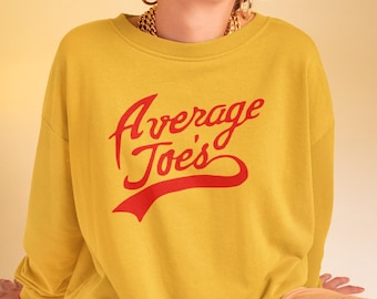 May include: Mustard yellow sweatshirt with the text "Average Joe's" in red script. The person in the image is wearing orange sunglasses and tan pants. The background is a light yellow.