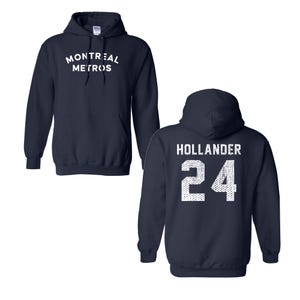 May include: A navy blue hooded sweatshirt featuring a front graphic with the white text MONTREAL METROS. The back of the hoodie displays the white text HOLLANDER above the number 24, both rendered in a distressed, textured white font style.