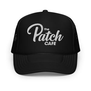 May include: Black trucker hat with the text "the Patch CAFE" embroidered in white script. The hat features a mesh back and a curved brim. A casual accessory for everyday wear.