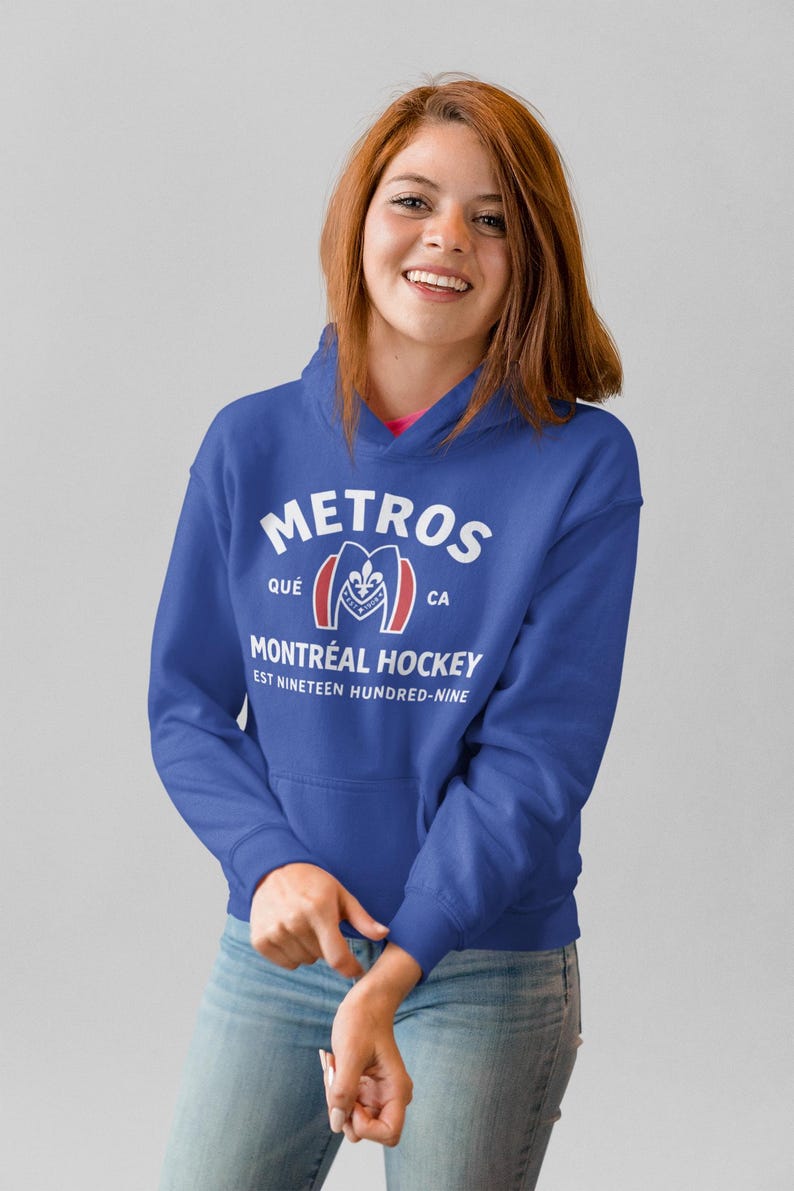 May include: A royal blue hooded sweatshirt featuring white text that reads METROS, QU&Eacute; CA, MONTR&Eacute;AL HOCKEY, and EST NINETEEN HUNDRED-NINE, with a central graphic of a stylized letter M containing a fleur-de-lis and the year 1909 in red and white.