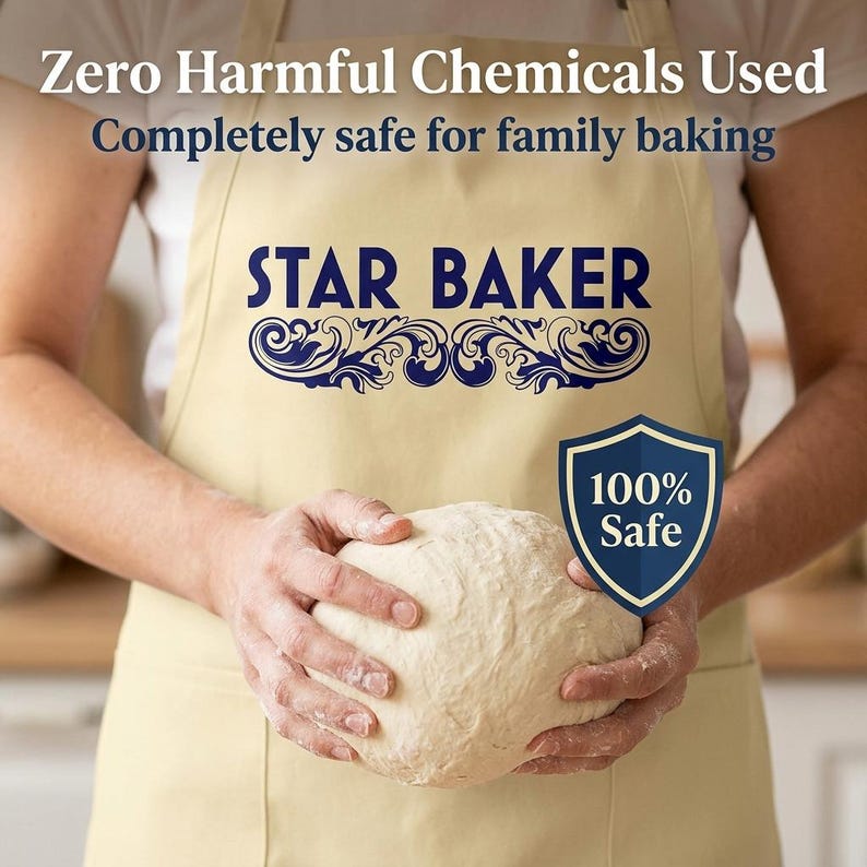 Op de afbeelding: Een beige schort met de donkerblauwe tekst STAR BAKER en decoratieve krullen. Het schort bevat de tekst Zero Harmful Chemicals Used, Completely safe for family baking en een blauw schildicoon met de tekst 100% Safe.