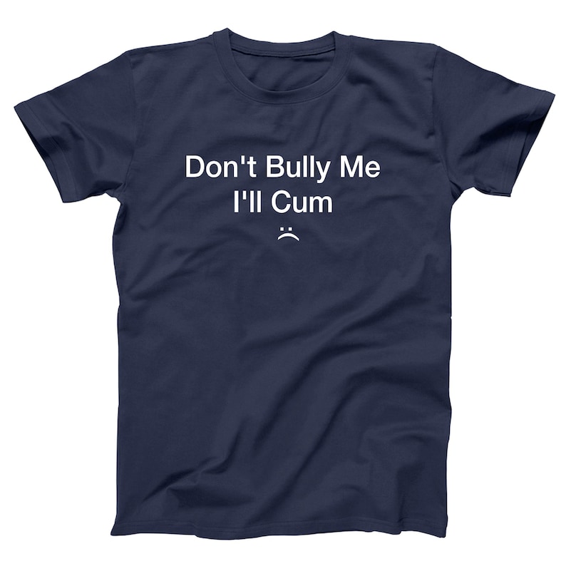 May include: Navy blue t-shirt with the text "Don't Bully Me I'll Cum" in white, along with a small, sad face emoji. The shirt is a casual wear item.