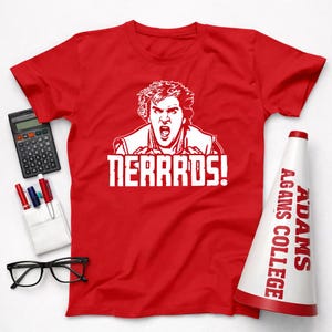 May include: A red t-shirt with a white graphic of a person yelling and the word "NERRDS!" in bold letters. A white and red megaphone with "ADAMS COLLEGE" printed on it is also visible.