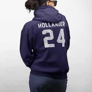 May include: A dark navy blue hooded sweatshirt featuring the text HOLLANDER and the number 24 printed in a white, textured, dot-patterned font on the back. The hoodie has long sleeves, a hood, and a standard fit, shown from the back view.