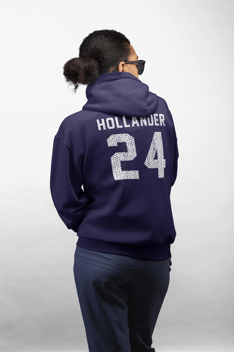 May include: A dark navy blue hooded sweatshirt featuring the text HOLLANDER and the number 24 printed in a white, textured, dot-patterned font on the back. The hoodie has long sleeves, a hood, and a standard fit, shown from the back view.