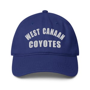 Puede incluir: Gorra de béisbol azul real con visera curva. La gorra presenta el texto bordado "WEST CANAAN COYOTES" en blanco, arqueado en la parte delantera. Es un estilo clásico y ajustable.