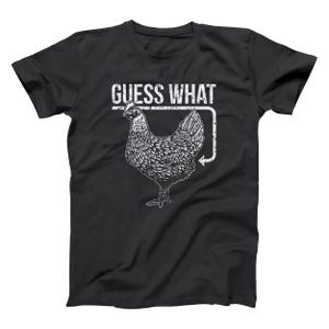 May include: Black t-shirt with a white graphic of a chicken and the text "GUESS WHAT". The chicken illustration is detailed, with a textured appearance. The design includes an arrow pointing towards the chicken, adding visual interest. A casual, everyday wear tee.