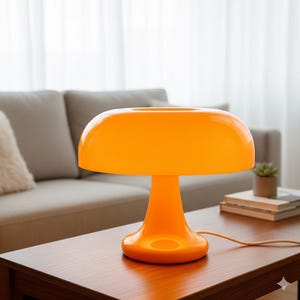 Puede incluir: Lámpara de mesa naranja brillante con forma de hongo. La lámpara tiene una pantalla redondeada y una base de pedestal. Está colocada sobre una mesa de madera. La lámpara está enchufada. El fondo incluye un sofá y una ventana. La lámpara mide unos 30 cm de alto.
