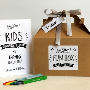 May include: A white coloring book with black text reading AWESOME! KIDS COLORING BOOK THANKS FOR COMING! Anna and Blake, a brown cardboard box with a gray ribbon and a tag reading Taylor, and a green box of crayons with red, yellow, and blue crayons.