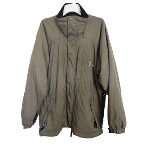 May include: Olive green jacket with a black collar and cuffs. The jacket has a button-up front, two pockets, and the word "Fan" embroidered on the chest. The jacket is hanging on a white hanger.