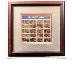 Può includere: Stampa incorniciata con un foglio di francobolli intitolato "Football Coaches". I francobolli sono disposti in righe e colonne, ognuno raffigurante un allenatore diverso. La cornice è di colore marrone scuro e il passe-partout è beige chiaro.