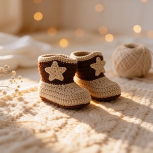 May include: A pair of handmade crochet baby booties featuring a two-tone design with a dark brown upper section and a cream-colored lower section. Each bootie is decorated with a cream-colored crocheted star appliqué on the outer side.