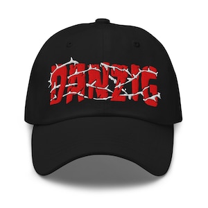 May include: Black baseball cap with the word "DANZIG" embroidered in red with white accents. The cap has a curved brim and an adjustable strap at the back. The hat is made of a durable fabric.