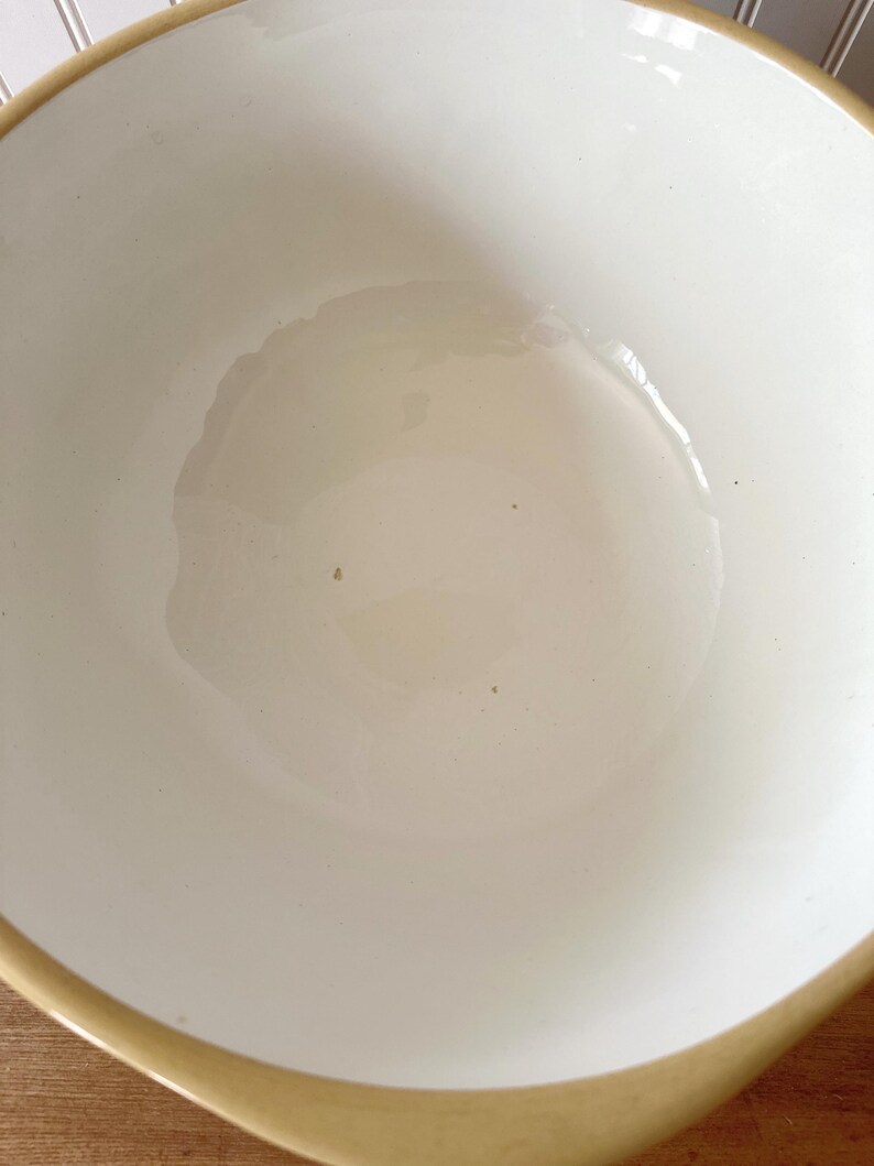 K&ouml;nnte beinhalten: Eine wei&szlig;e Keramik-R&uuml;hrsch&uuml;ssel mit beigem Rand. Die Sch&uuml;ssel hat eine glatte, gl&auml;nzende Oberfl&auml;che und eine abgerundete Form. Im Inneren der Sch&uuml;ssel scheint sich eine fl&uuml;ssige Substanz zu befinden.