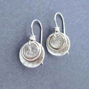 May include: Silver dangle earrings with a clear crystal stone set in a hammered silver circle.