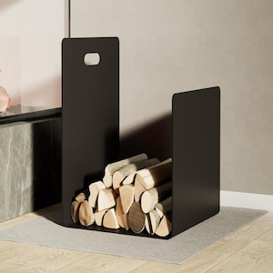 Peut inclure: Un porte-bûches en métal noir mat au design ouvert, doté d'une poignée découpée rectangulaire sur le dessus. Le support est rempli d'une pile de bûches de bois fendues de couleur claire et de tailles variées, disposées horizontalement.