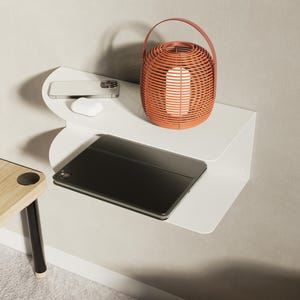 Puede incluir: Un estante de pared blanco de dos niveles con bordes curvos. El nivel superior sostiene un teléfono inteligente, auriculares inalámbricos blancos y una linterna naranja redonda. El nivel inferior sostiene una tableta negra cerrada.