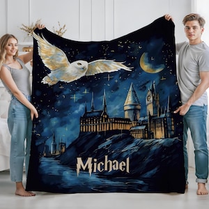 May include: A dark blue blanket featuring a nighttime scene with a white owl in flight, a castle, and a crescent moon. The name "Michael" is printed in a stylized font at the bottom. The blanket is held by two people.