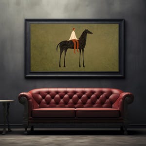 May include: An art print featuring a minimalist illustration of a person riding a black horse. The artwork is framed in black and hangs above a red tufted leather sofa. A small side table is to the left.