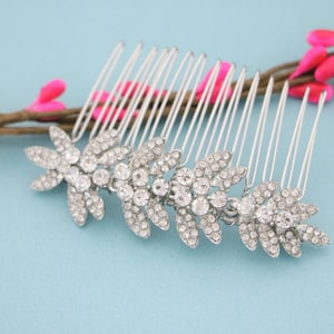 May include: Silver hair comb with three crystal leaf designs. The comb has a row of teeth on the back.